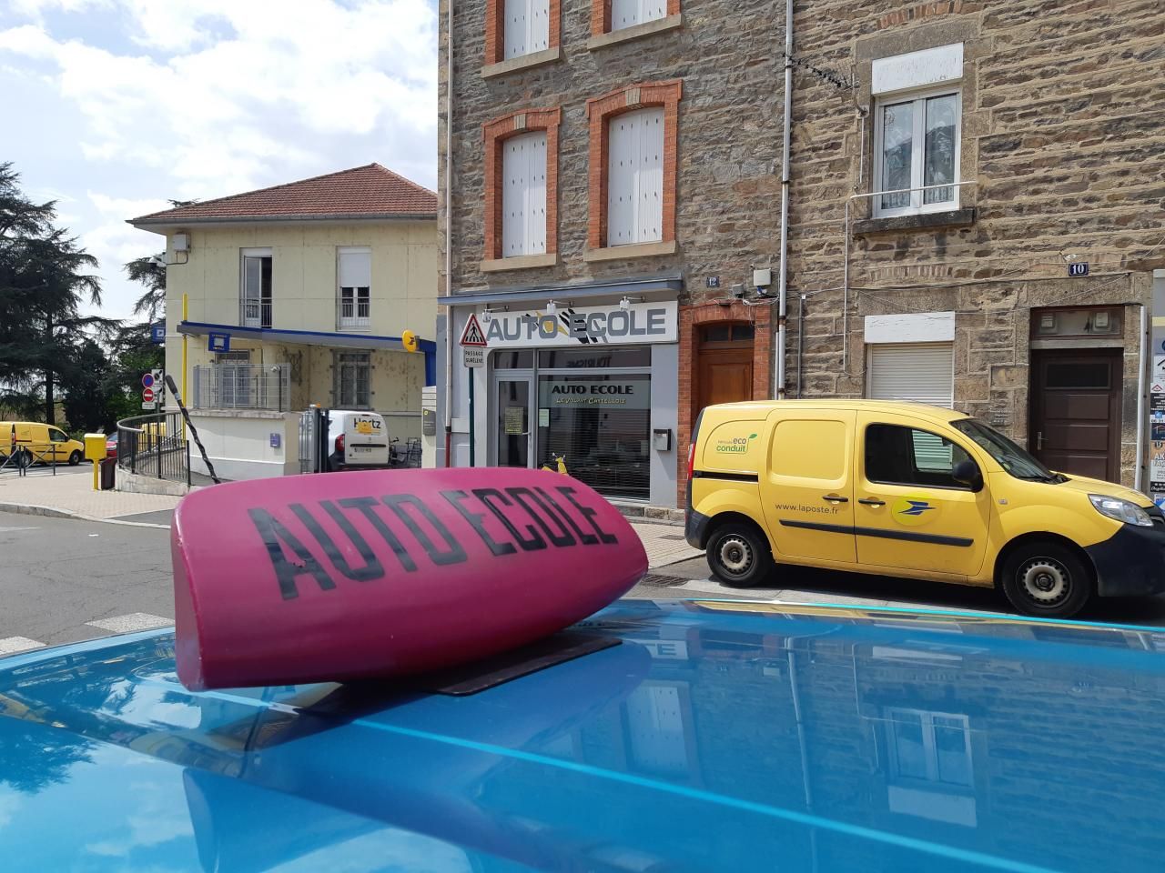 Façade d'une auto-école avec véhicules