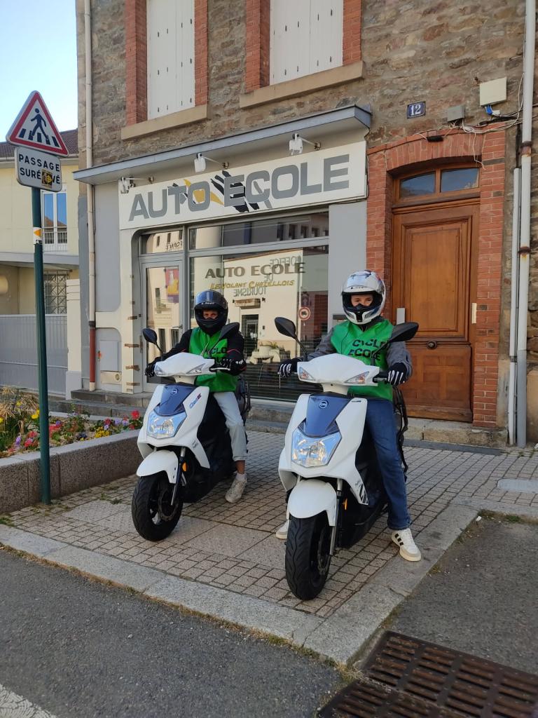 Deux personnes en scooter devant une auto-école